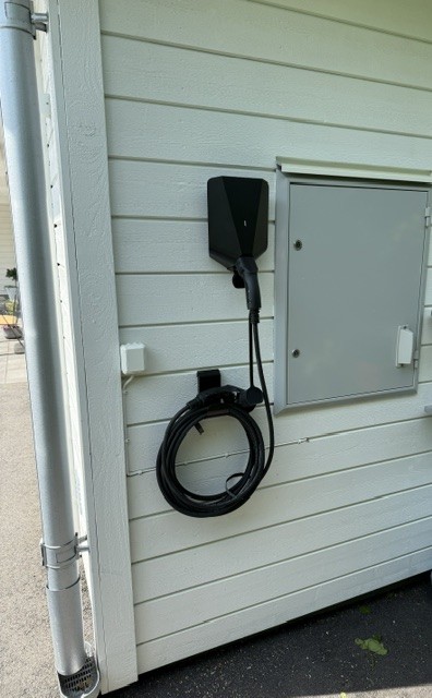 Installerad laddbox på husvägg med kabel och elskåp